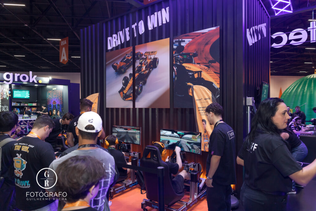 Público testa simuladores automobilísticos da Logitech com volante RS50 e acessórios voltados para jogos de corrida.