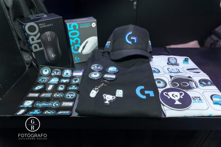 Itens da Logitech G com mouse, boné, camiseta e adesivos conquistados nas ativações do estande.