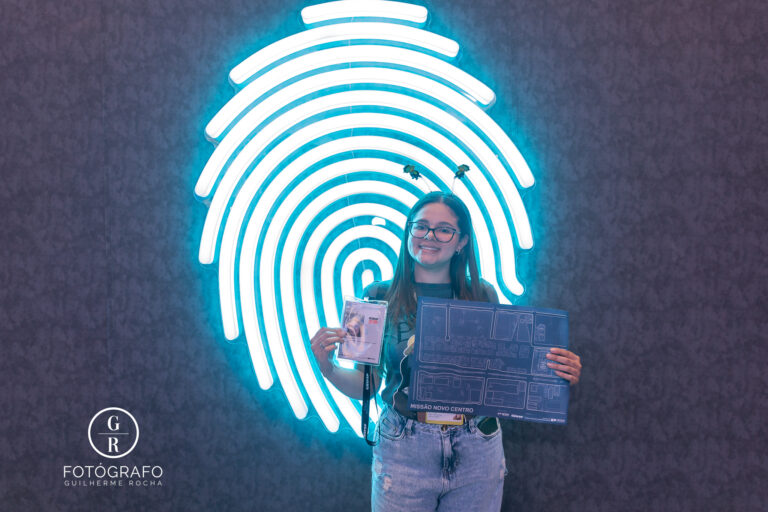 Participante no estande da Cultura SP exibindo credencial de agente e mapa após completar desafios interativos.
