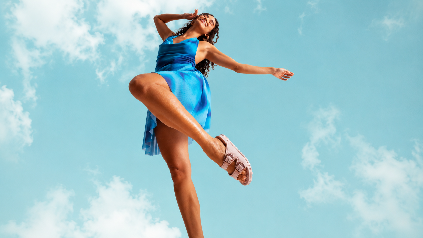 Modelo usando sandália plataforma da Zaxy com vestido azul fluido em ensaio fashion ao ar livre, fotografada em ângulo baixo contra céu azul claro, destacando conforto, leveza e estilo casual da coleção Zaxy.