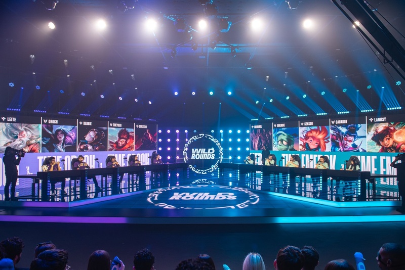 Arena competitiva da Riot Games durante final presencial do Wild Rounds com jogadores de Wild Rift, telões iluminados e torcida acompanhando as partidas em São Paulo.