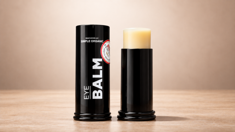 Simple Organic Eye Balm apresentado em embalagem preta ao lado do balm aberto, evidenciando a fórmula em bastão desenvolvida para hidratação da área dos olhos.