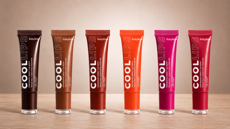 Coleção completa Ruby Rose Cool Lips com seis hidratantes labiais coloridos alinhados sobre superfície de madeira. A imagem apresenta as embalagens nas cores marrom, nude, terracota, coral, rosa vibrante e rosa avermelhado, evidenciando a variedade de tons e a identidade visual da linha Ruby Rose.