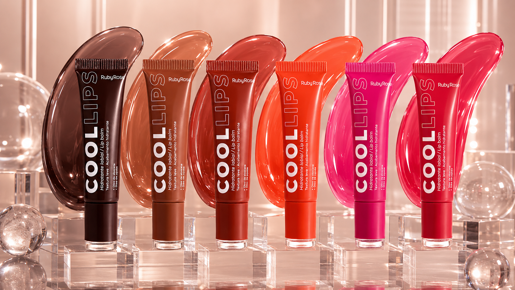 Linha Ruby Rose Cool Lips com seis hidratantes labiais coloridos exibidos sobre bases transparentes. Os produtos aparecem em tons marrom, nude, terracota, coral, rosa vibrante e rosa avermelhado, acompanhados por manchas de gloss ao fundo que representam cada cor da coleção. O cenário possui acabamento sofisticado, iluminação suave e elementos transparentes que destacam a proposta de hidratação e brilho da linha Ruby Rose.