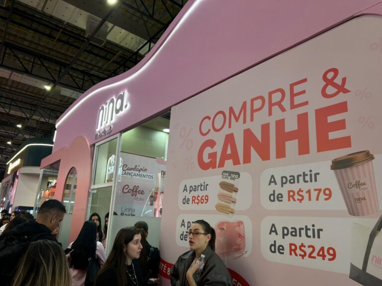 Área promocional da Nina Make Up na Beauty Show 2026 exibe ofertas especiais e campanha "Compre & Ganhe", incentivando compras e interação com os visitantes.