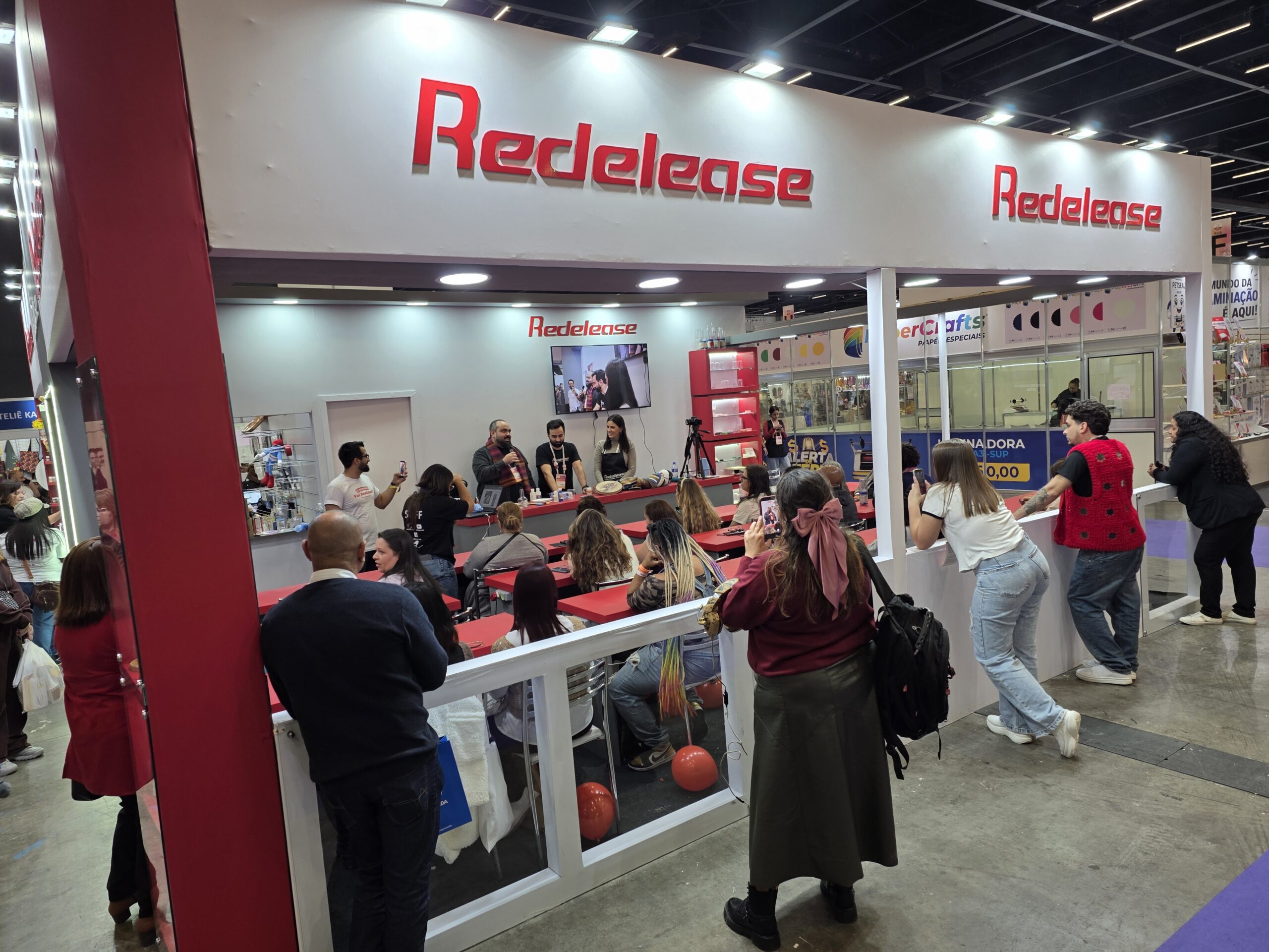 Área de cursos da Redelease reúne visitantes durante demonstração prática de resina, reforçando o caráter educativo e interativo do estande.