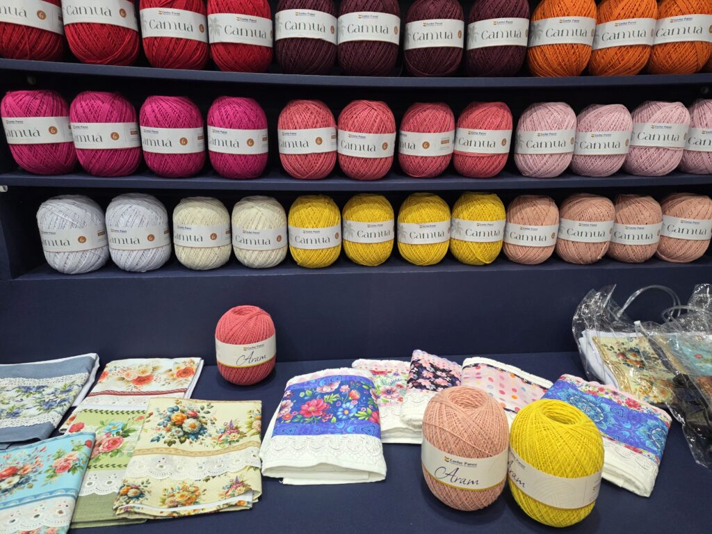 Fios coloridos e peças personalizadas reforçam a diversidade de materiais oferecidos pela Center Panos aos artesãos.
