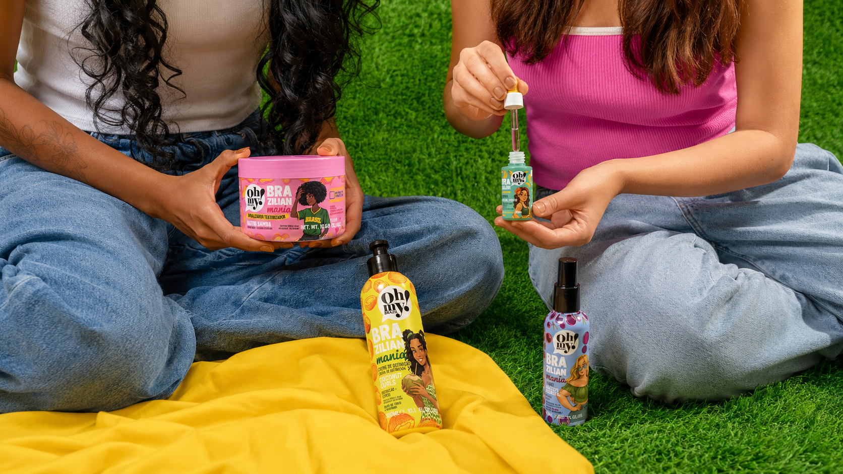 Produtos da Oh My! Brazil da linha Brazilian Mania aparecem em um piquenique ao ar livre, com duas mulheres utilizando os finalizadores capilares, reforçando a proposta de cuidado, leveza e beleza inspirada no Brasil.