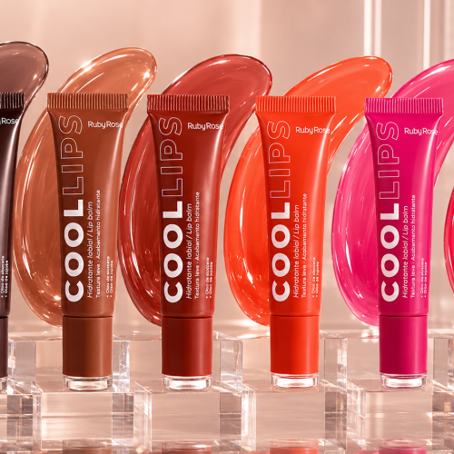 Linha Ruby Rose Cool Lips com seis hidratantes labiais coloridos exibidos sobre bases transparentes. Os produtos aparecem em tons marrom, nude, terracota, coral, rosa vibrante e rosa avermelhado, acompanhados por manchas de gloss ao fundo que representam cada cor da coleção. O cenário possui acabamento sofisticado, iluminação suave e elementos transparentes que destacam a proposta de hidratação e brilho da linha Ruby Rose.