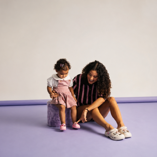 Mãe e filha usando calçados Zaxy em ensaio minimalista com fundo lilás, destacando conforto, estilo e modelos customizáveis da coleção de Dia das Mães da Zaxy.