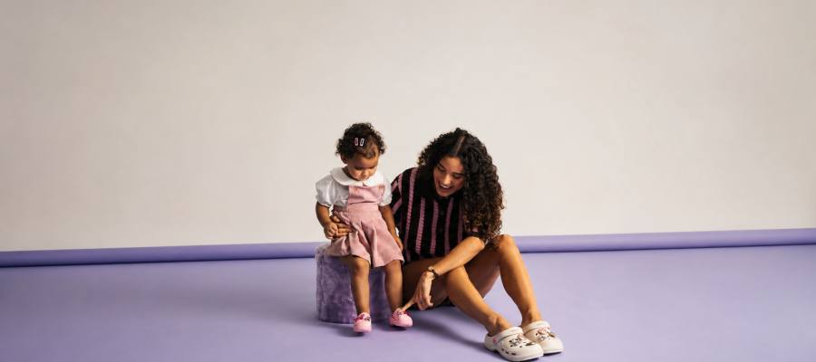 Mãe e filha usando calçados Zaxy em ensaio minimalista com fundo lilás, destacando conforto, estilo e modelos customizáveis da coleção de Dia das Mães da Zaxy.