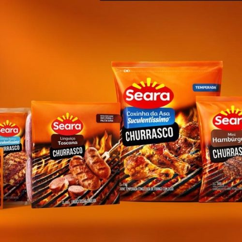 Seara apresenta novos produtos da linha churrasco em embalagem promocional durante divulgação da APAS Show 2026, com linguiças, hambúrgueres, coxinha da asa e pasta de alho sobre fundo alaranjado.