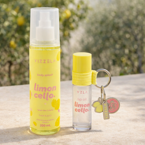 Body Splash e Lip Oil Limoncello vizzela posicionados sobre superfície de pedra com limoeiros ao fundo, embalagem amarela cítrica inspirada na atmosfera italiana.