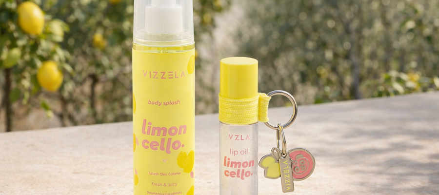 Body Splash e Lip Oil Limoncello vizzela posicionados sobre superfície de pedra com limoeiros ao fundo, embalagem amarela cítrica inspirada na atmosfera italiana.