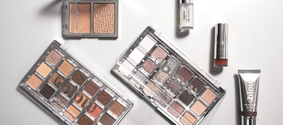 Imagem da linha Blow da Ruby Rose com paletas de sombras em tons neutros e glow, lip oil, iluminador líquido e base glow, dispostos sobre fundo claro.