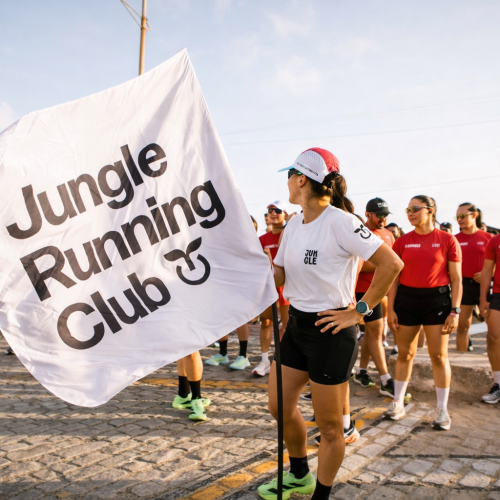 Grupo de corredores em ação ao ar livre, com bandeira do Jungle Running Club, representando energia, movimento e Plant Power.