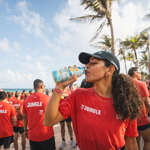 Jungle Low-Carb Maracujá sendo consumido durante evento ao ar livre na praia, reforçando hidratação diária em dias quentes.