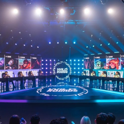 Arena competitiva da Riot Games durante final presencial do Wild Rounds com jogadores de Wild Rift, telões iluminados e torcida acompanhando as partidas em São Paulo.